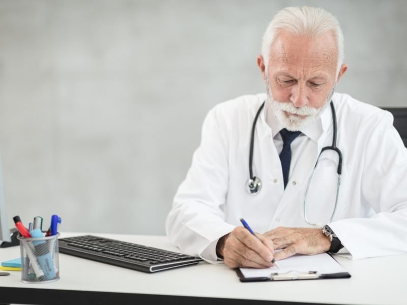 A doctor writing notes at his desk